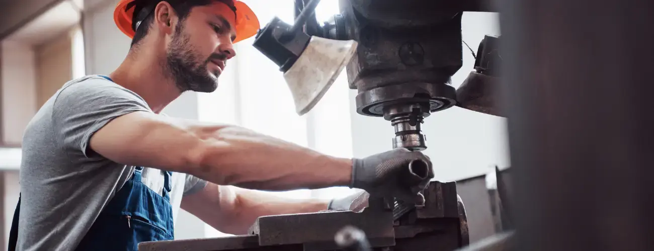 meisterwerk - Handwerker Versicherungen. Handwerker arbeitet an großer Maschine